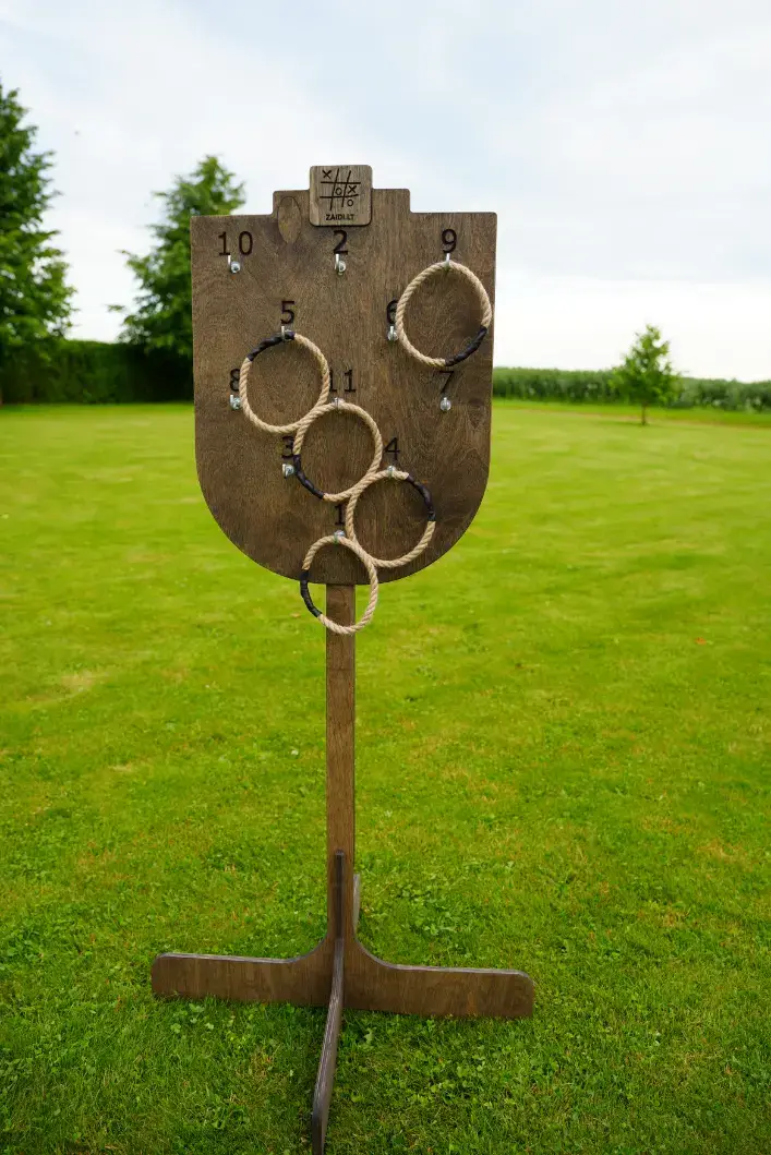 Medinis taiklumo žaidimas „Žiedų karalius“ – virviniai žiedai metami į vertikaliai stovinčią taikinio lentą.