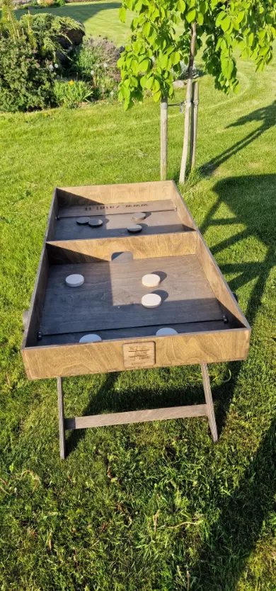 Medinis lauko žaidimas „Skraidančios šaškės“ su išdėliotomis medinėmis šaškėmis ant stalo. Lauko žaidimų gaminimas Lietuvoje, Medžio karma