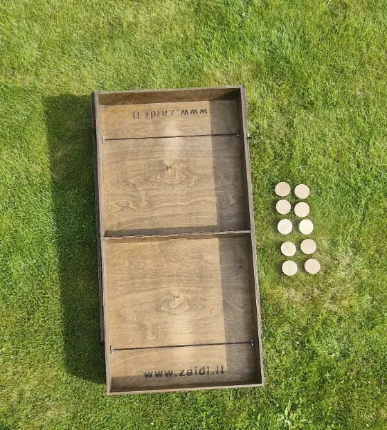 Medinis lauko žaidimas „Skraidančios šaškės“ su išdėliotomis medinėmis šaškėmis ant stalo. Lauko žaidimų gaminimas Lietuvoje, Medžio karma