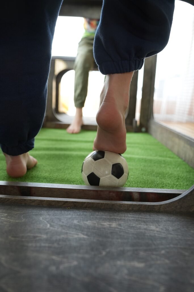 Medžio Karma kojinis futbolas subsoccer – du žaidėjai kojomis varžosi dėl kamuolio ant dirbtinės žolės laukelio