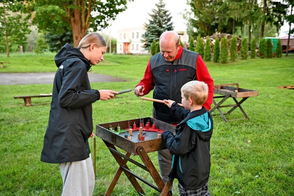 Žvejybos žaidimo detalės iš arti – žalios medinės žuvelės su kabliukais ant spalvotos lentos