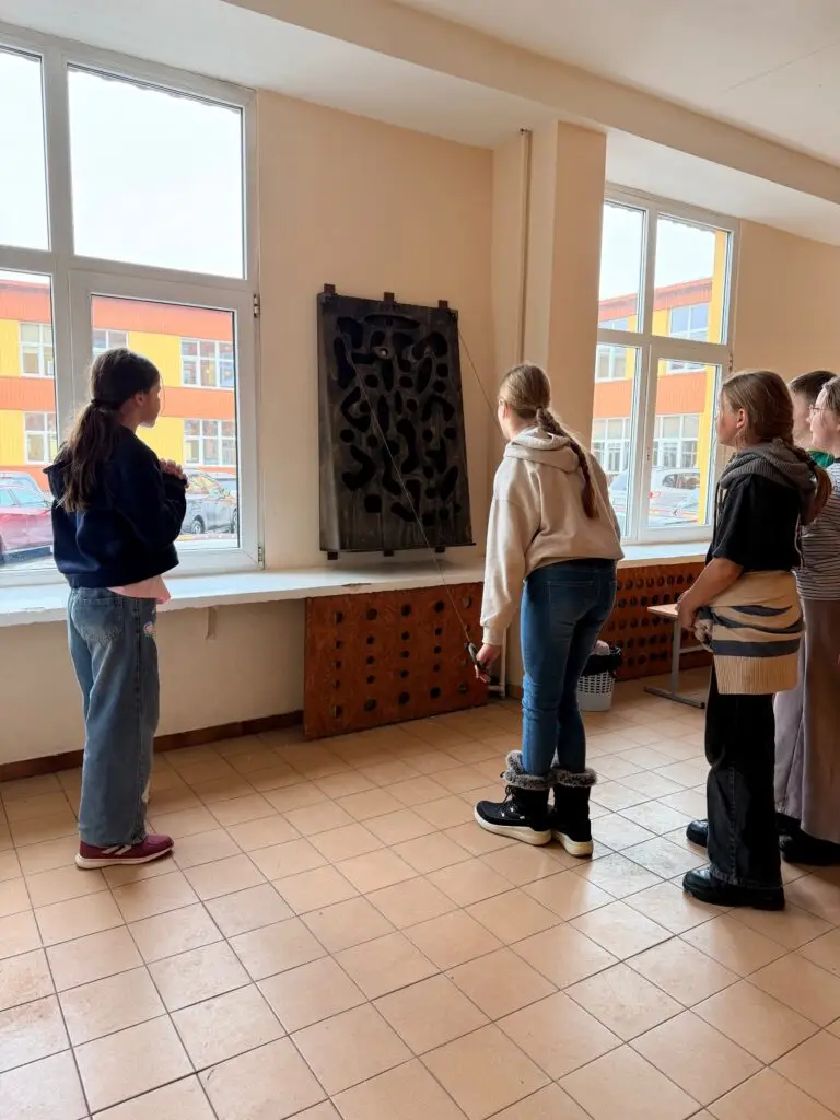 Mokinys žaidžia medinį žaidimą Korys mokyklos koridoriuje – aktyvios pertraukos žaidimas be telefono. lauko žaidimų gamyba mokykloms medžio karma