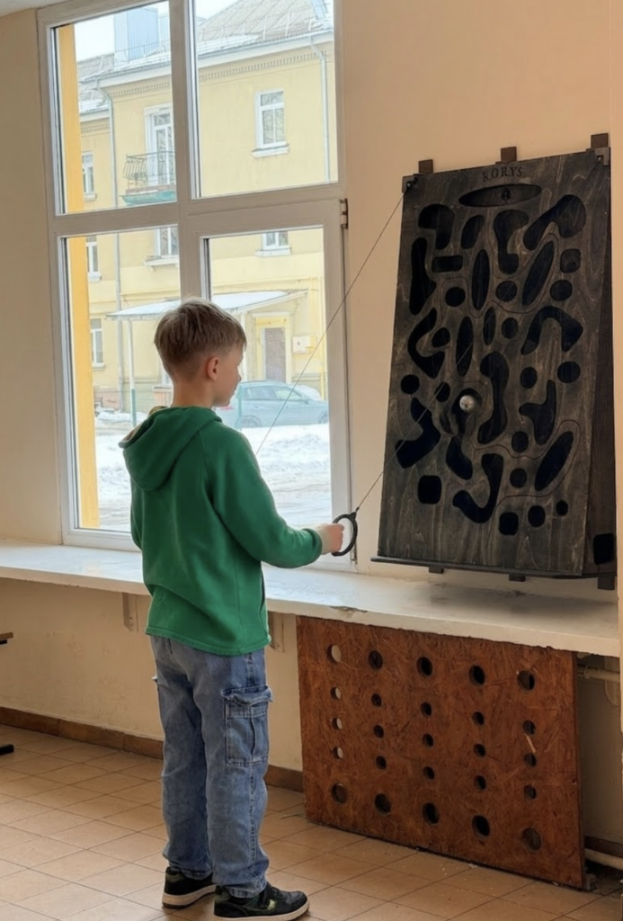 Mokinys žaidžia medinį žaidimą Korys mokyklos koridoriuje – aktyvios pertraukos žaidimas be telefono