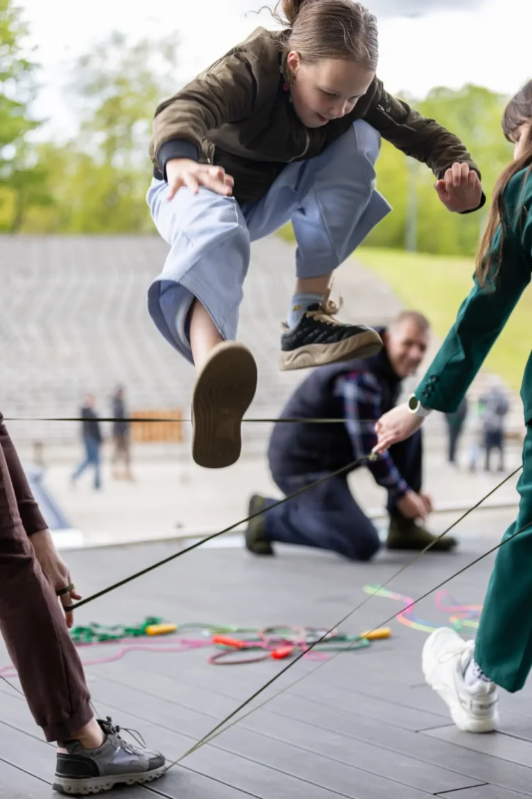 Vaikai šokinėja per gumytę – judrūs kiemo žaidimai festivalyje Šiauliuose